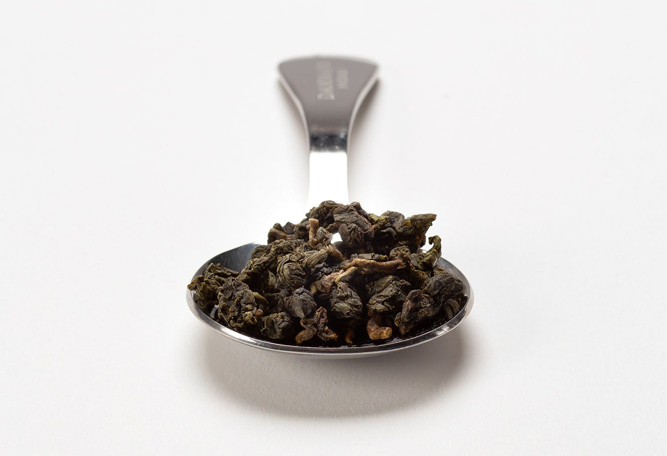 Stainless steel measuring spoon with oolong tea in bulk.